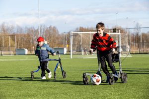 Framevoetbal: kinderen in een loopframe spelen voetbal.